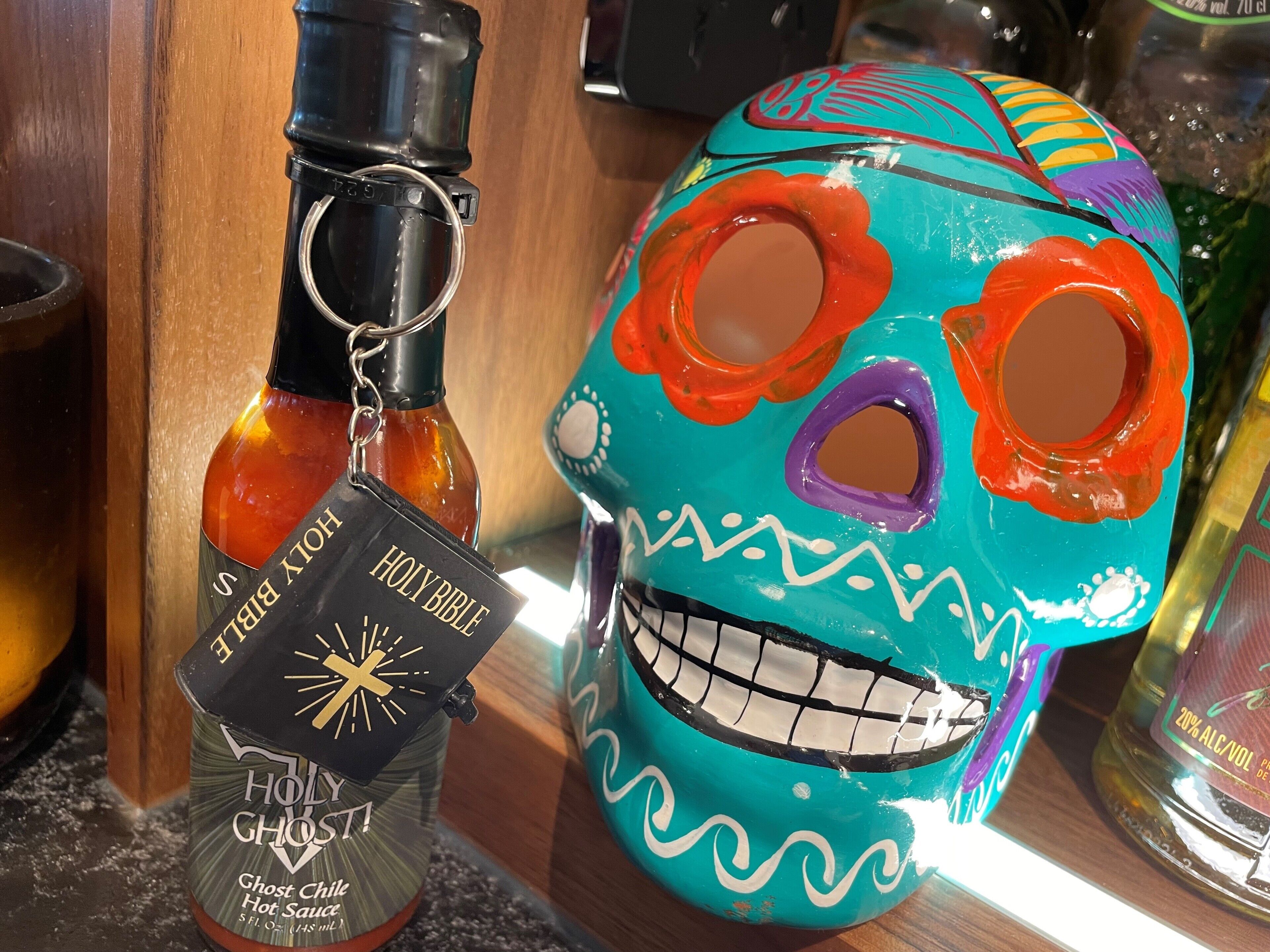 A bottle of Holy Ghost Hot Sauce and a colorful skull decoration on a counter.