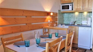 Cocina compacta con armarios de madera, un microondas y un lavavajillas.