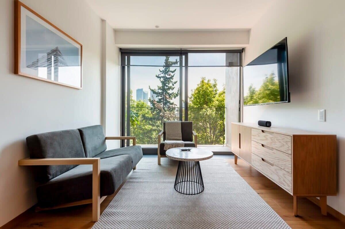 A modern living room with a sofa, a round coffee table, a chair, a TV, and a wooden cabinet.