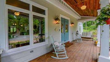 Une véranda en bois avec un revêtement blanc, une chaise berçante et un banc.