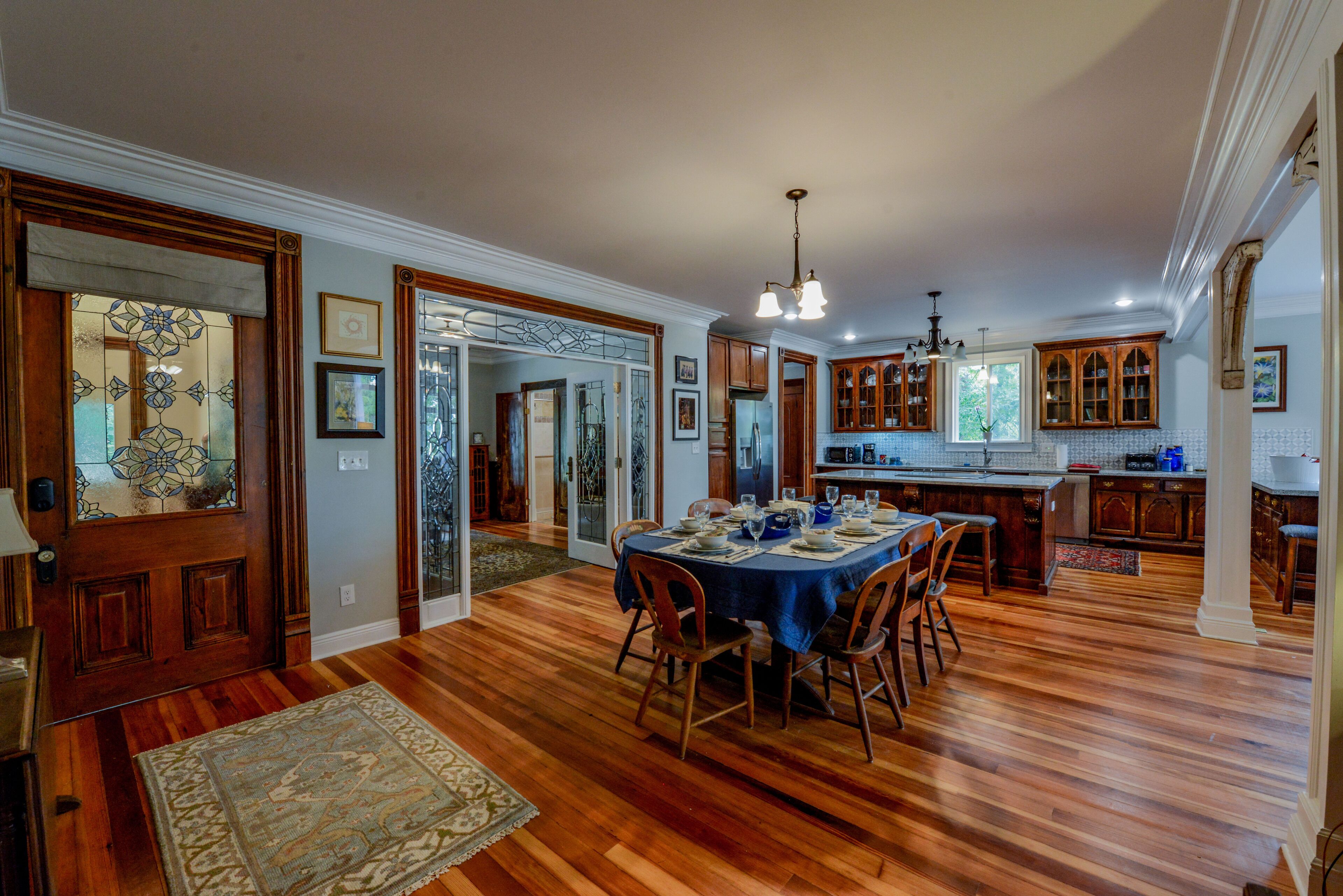 Une salle à manger spacieuse avec un plancher en bois, une table à manger dressée pour six personnes et un lustre.