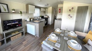 A compact, modern RV interior with a kitchen, dining area, and living space. - Beautiful 3BR Holiday Home in Stunning Location - Pass the Keys (Moffat)
