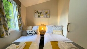 A hotel room with two beds, a window with curtains, a wall-mounted lamp, and a painting above the beds. - Beautiful 3BR Holiday Home in Stunning Location - Pass the Keys (Moffat)