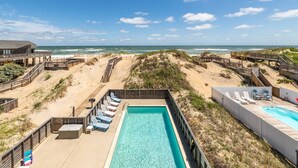 A beachside resort with a swimming pool, beach chairs, and a wooden deck overlooking the ocean. - Anchored at Last - S Nags Head MP 19.5, Oceanfront, Pool, Hot Tub, Kiddie Pool, Pool Table (Nags Head)