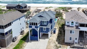 A beachfront property with a two-story house featuring a large balcony, a swimming pool, and a view of the ocean. - Anchored at Last - S Nags Head MP 19.5, Oceanfront, Pool, Hot Tub, Kiddie Pool, Pool Table (Nags Head)