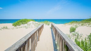 A wooden boardwalk leading to a sandy beach with a clear blue sky. - Anchored at Last - S Nags Head MP 19.5, Oceanfront, Pool, Hot Tub, Kiddie Pool, Pool Table (Nags Head)