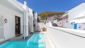 A residential area with a swimming pool, white buildings, and a hillside in the background. - Spacious Modern Home in iconic Green Point (Cape Town)