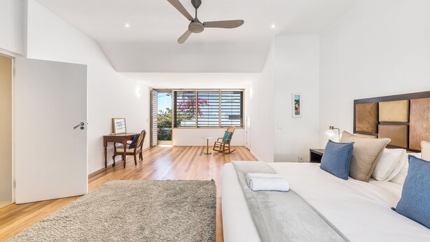 A modern bedroom with a large bed, a ceiling fan, a desk, and a view of the outdoors. - Spacious Modern Home in iconic Green Point (Cape Town)