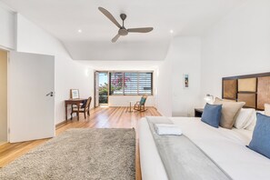 A modern bedroom with a large bed, a ceiling fan, a desk, and a view of the outdoors. - Spacious Modern Home in iconic Green Point (Cape Town)
