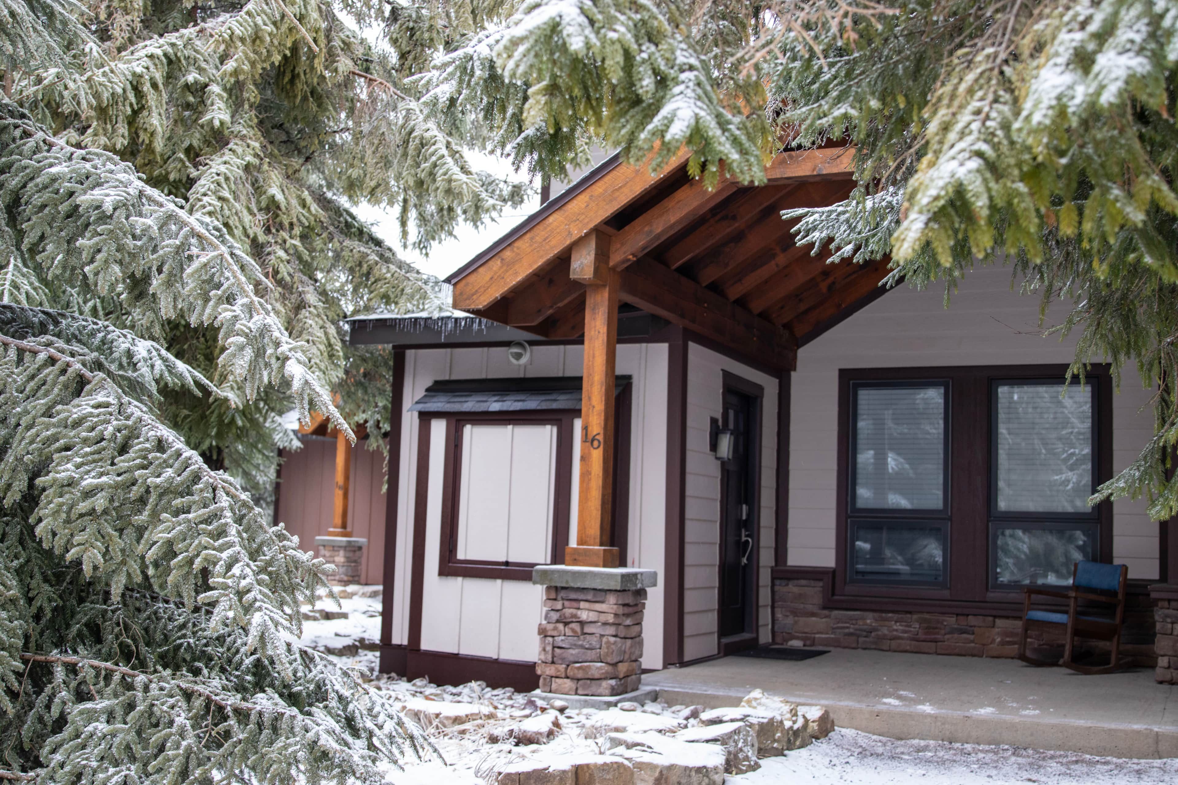 Un bâtiment en bois, avec des fondations en pierre, un porche et une porte.