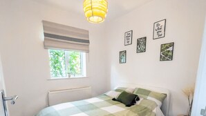 Un dormitorio con cama, ventana con persianas, radiador y decoración en la pared.