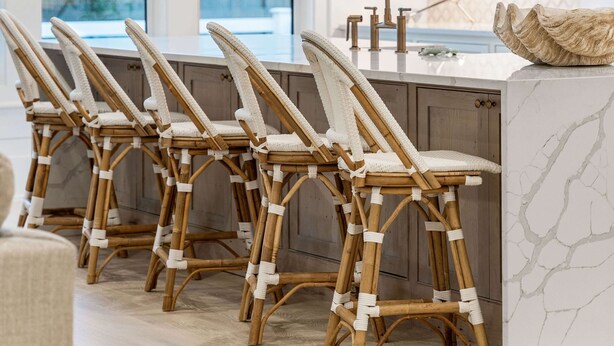 Une cuisine moderne avec des meubles blancs, un îlot en marbre et un luminaire suspendu original en forme de feuille.