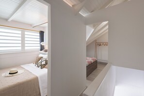 A bedroom with a bed, a nightstand, a lamp, and a window with blinds.