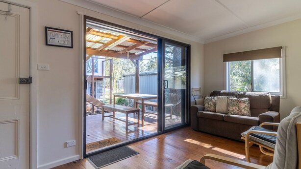 Ein Zimmer mit einer Schiebetür zu einer Außenpatio-Terrasse mit Holzdeck und Tisch.