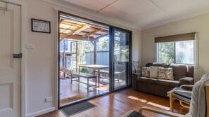 Ein Zimmer mit einer Schiebetür zu einer Außenpatio-Terrasse mit Holzdeck und Tisch.