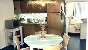 Een moderne keuken met donkere tegels, houten kastjes en een eethoek met een ronde tafel en stoelen.