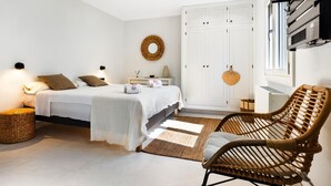 A bedroom with a bed, bedside tables, a wardrobe, a wicker chair, and a wall-mounted air conditioning unit. - Villa Gioia (Tolleric)
