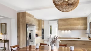 A modern kitchen with wooden cabinets, stainless steel appliances, and a dining area with a wooden table and chairs. - Villa Gioia (Tolleric)