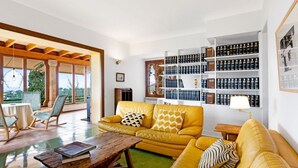 A spacious living room with a yellow sofa, wooden coffee table, and a bookshelf filled with books. - Villa Genova (Palma de Mallorca)