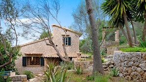 A stone house with a tiled roof, surrounded by trees and plants. - Villa Genova (Palma de Mallorca)