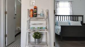 A room with a wooden-framed shelf holding toiletries, a bicycle decoration, and a bed with a dark headboard.