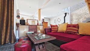A living room with a red sofa, a wooden coffee table, and a patterned curtain. - Quiet town house 2km from Ile de Ré bridge (La Rochelle)