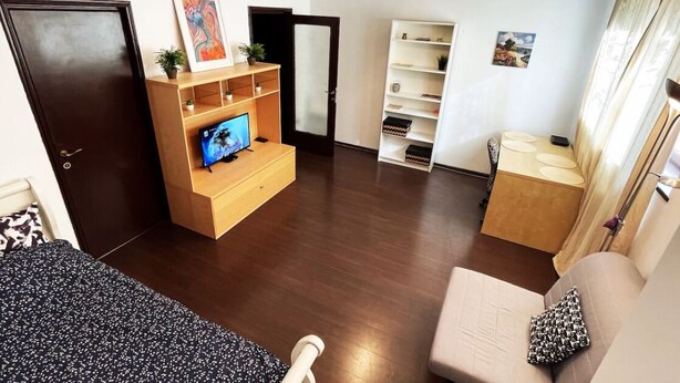A compact living space with a wooden entertainment unit, a sofa, a small table, and a bookshelf.