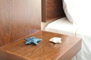 Una mesita de noche de madera con dos objetos en forma de estrella, uno azul y otro blanco, en una habitación de hotel.