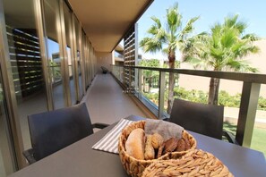 Een balkon met een tafel, stoelen en een mand met brood.