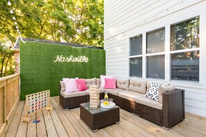 An outdoor patio with a green wall, wicker furniture, and a jigsaw puzzle game. - Elvis & Music City themed Nashville home | sleeps 12, patio, 4 baths (Nashville)