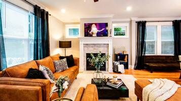 A modern living room with a fireplace, a large TV, and a cozy seating area.