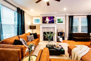 A modern living room with a fireplace, a large TV, and a cozy seating area. - Elvis & Music City themed Nashville home | sleeps 12, patio, 4 baths (Nashville)