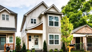 A row of modern two-story houses with front porches, a well-maintained lawn, and a mailbox.