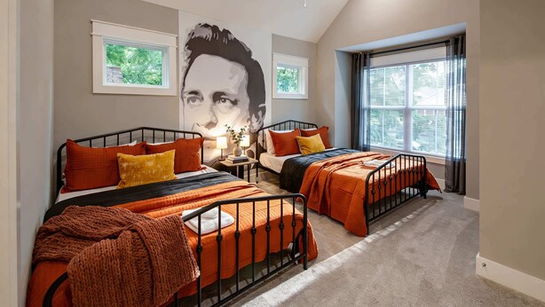 A bedroom with two beds, a ceiling fan, and a large window. - Elvis-themed Nashville home | sleeps 12, 4 bedrooms, patio & garage (Nashville)