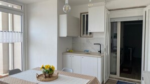 A compact kitchen with white cabinets, a marble backsplash, and a small window.