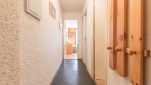 Un couloir avec un mur à texture, un plancher noir et des portes en bois.