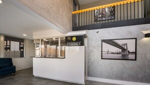 A reception area with a white counter, a sign reading "ESSENCE", and a framed picture of a bridge on the wall.