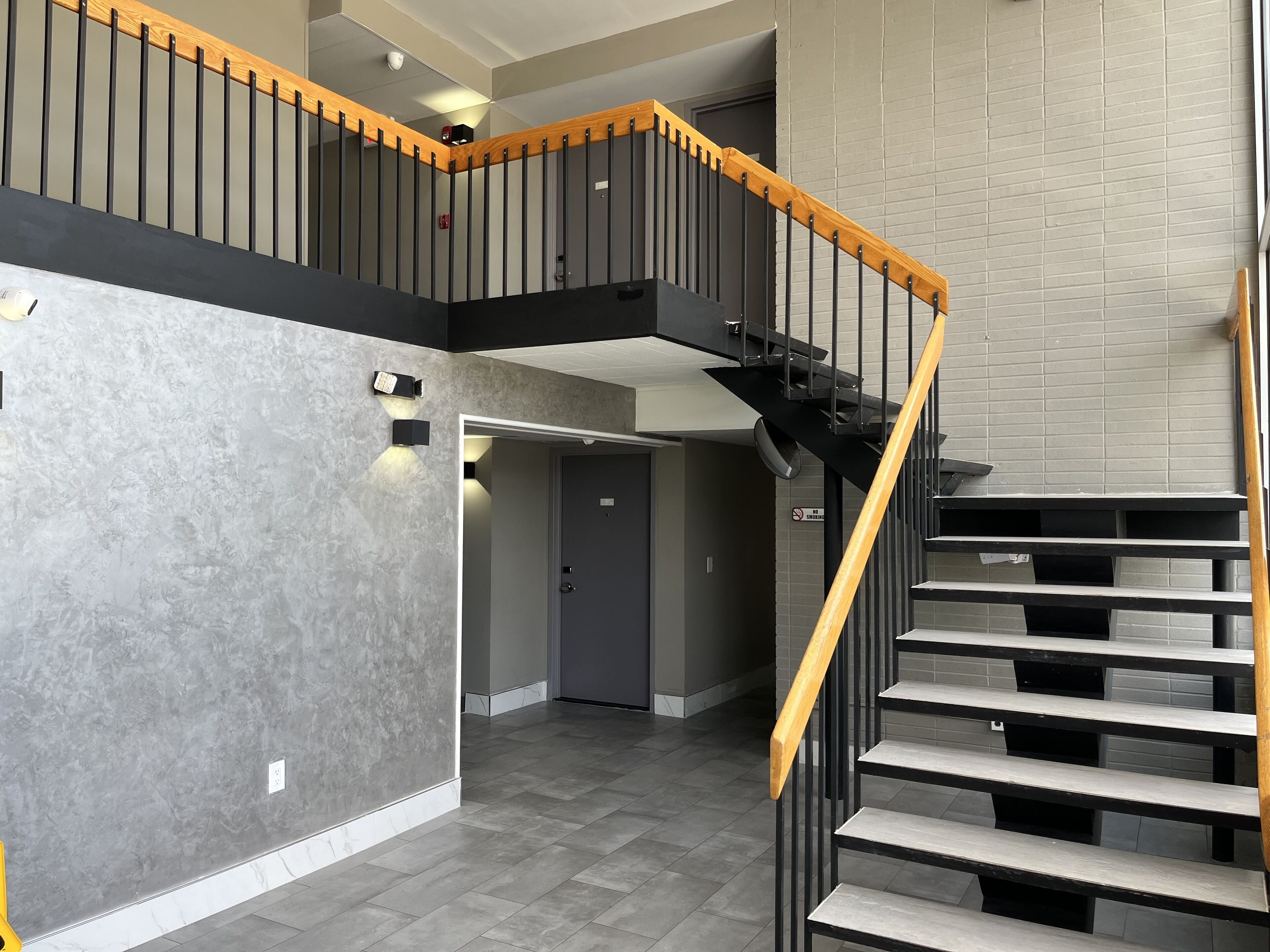 A modern interior with a staircase, grey walls, and a tiled floor.