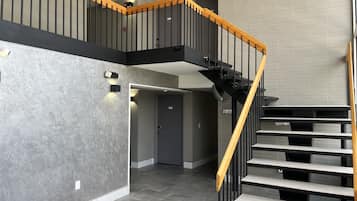 A modern interior with a staircase, grey walls, and a tiled floor.