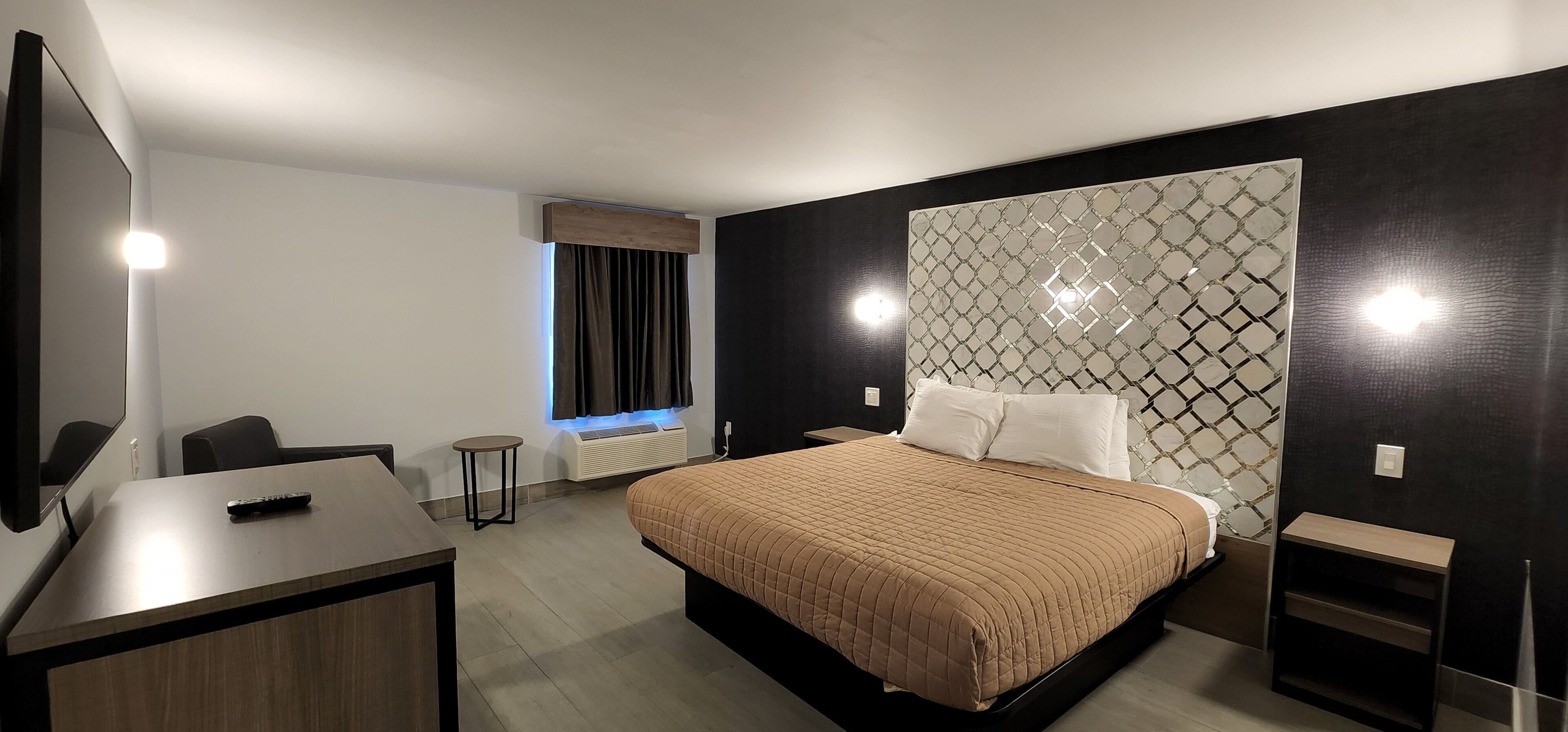 A modern hotel room with a large bed, a desk, and a chair.