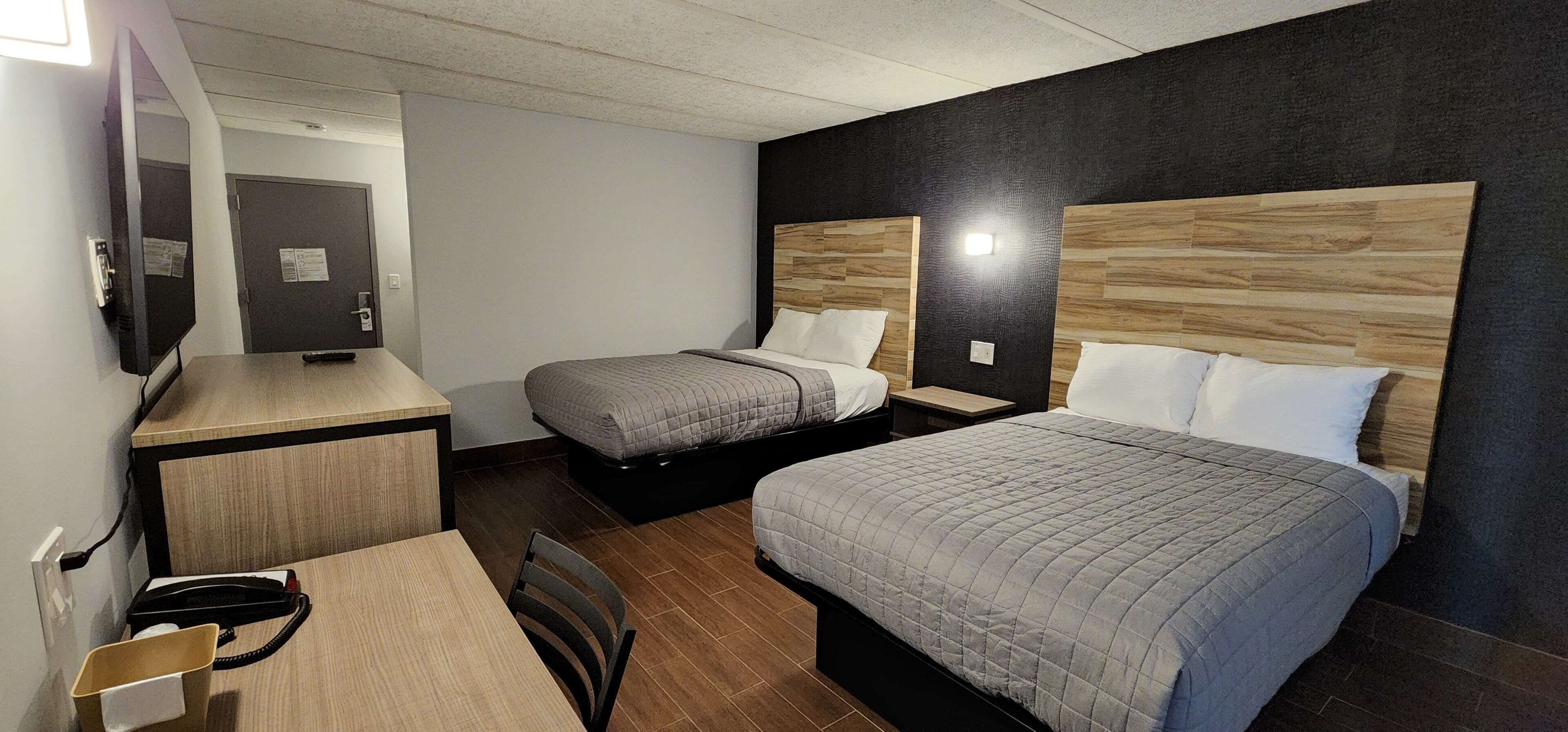A hotel room with two beds, a desk, and a chair.