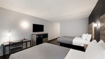 A hotel room with a bed, a desk with a lamp, a television, and a wall-mounted light fixture.
