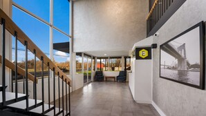 A modern interior with a staircase, seating area, and a large window offering a view of the outdoors.