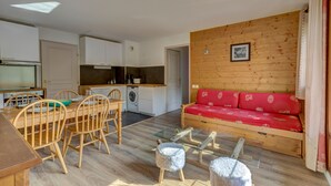 A compact living space with a dining area, kitchenette, and a red sofa.