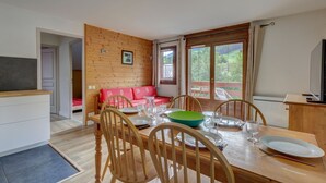 A dining area with a wooden table, chairs, and a red sofa.