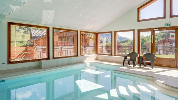 A swimming pool with clear views of a mountainous landscape through large windows.