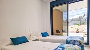 Habitación de hotel con dos camas, una mesita de noche y un ventanal con vista a la ciudad.