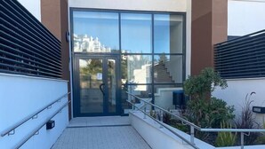 A modern building entrance with a glass door, a tiled pathway, and a metal railing. - AL BORADA HOMES 3-Bedroom Apartment with Terrace in a Premium Residential Complex in Marbella (Benahavís)