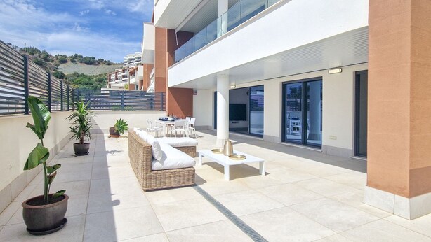 A modern outdoor patio with a seating area, potted plants, and a view of the surrounding hillside. - AL BORADA HOMES 3-Bedroom Apartment with Terrace in a Premium Residential Complex in Marbella (Benahavís)