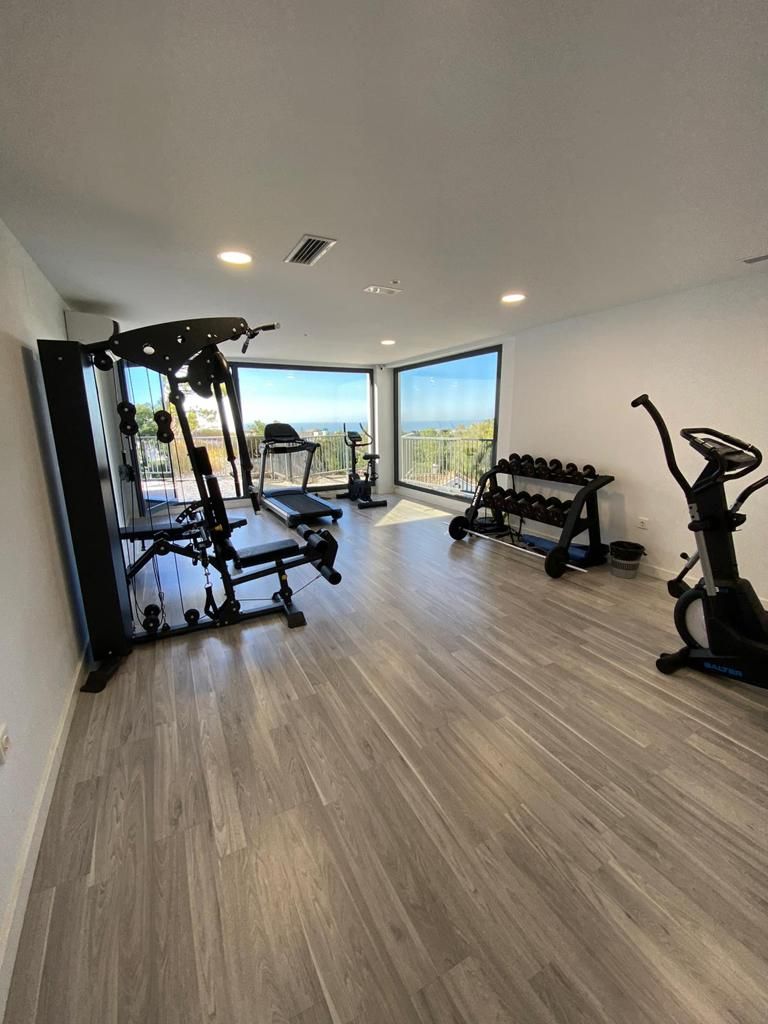 A spacious gym with a treadmill, elliptical, and weight bench.